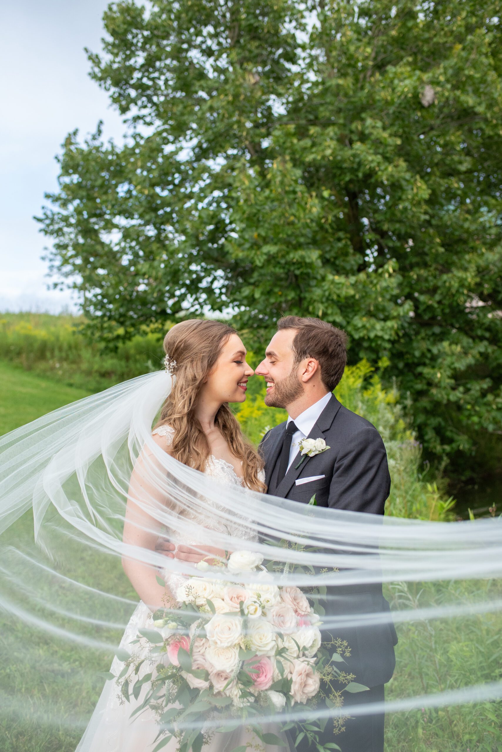 Bride and groom nose to nose with veil flowing around them at Sydenham Ridge Estate.