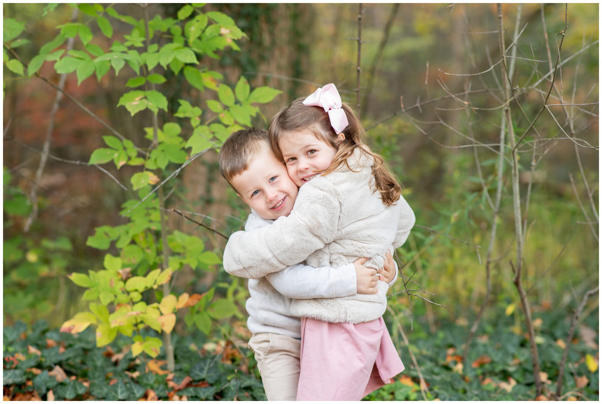 Two kids hugging in fall leaves at Springbank Gardens in London Ontario