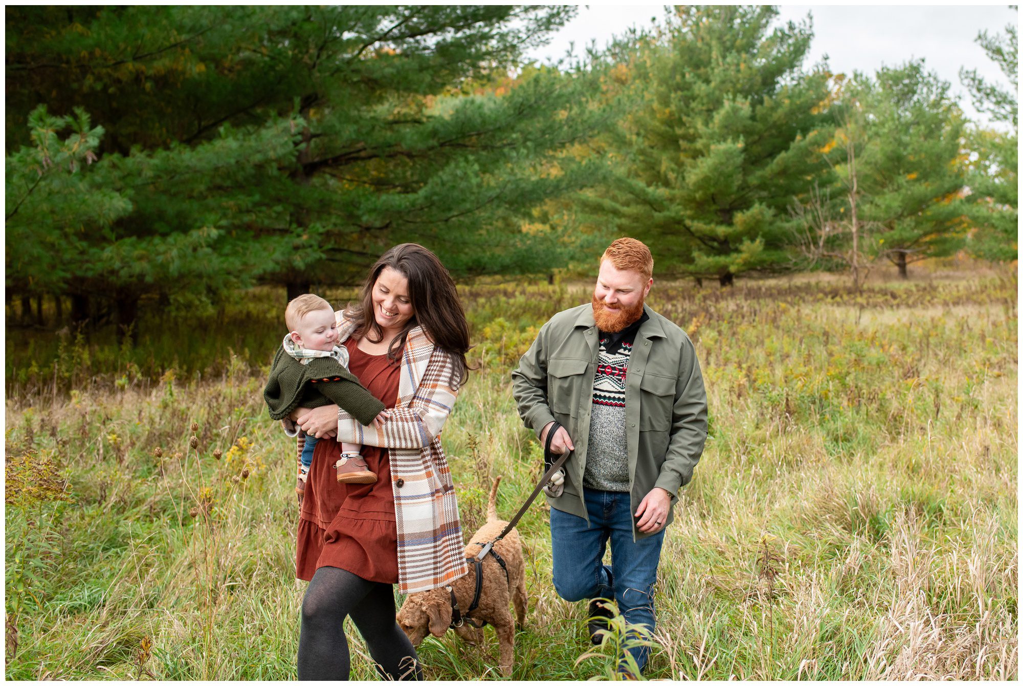 Family of three walking through the grass at Komoka Provincial Park in the fall.