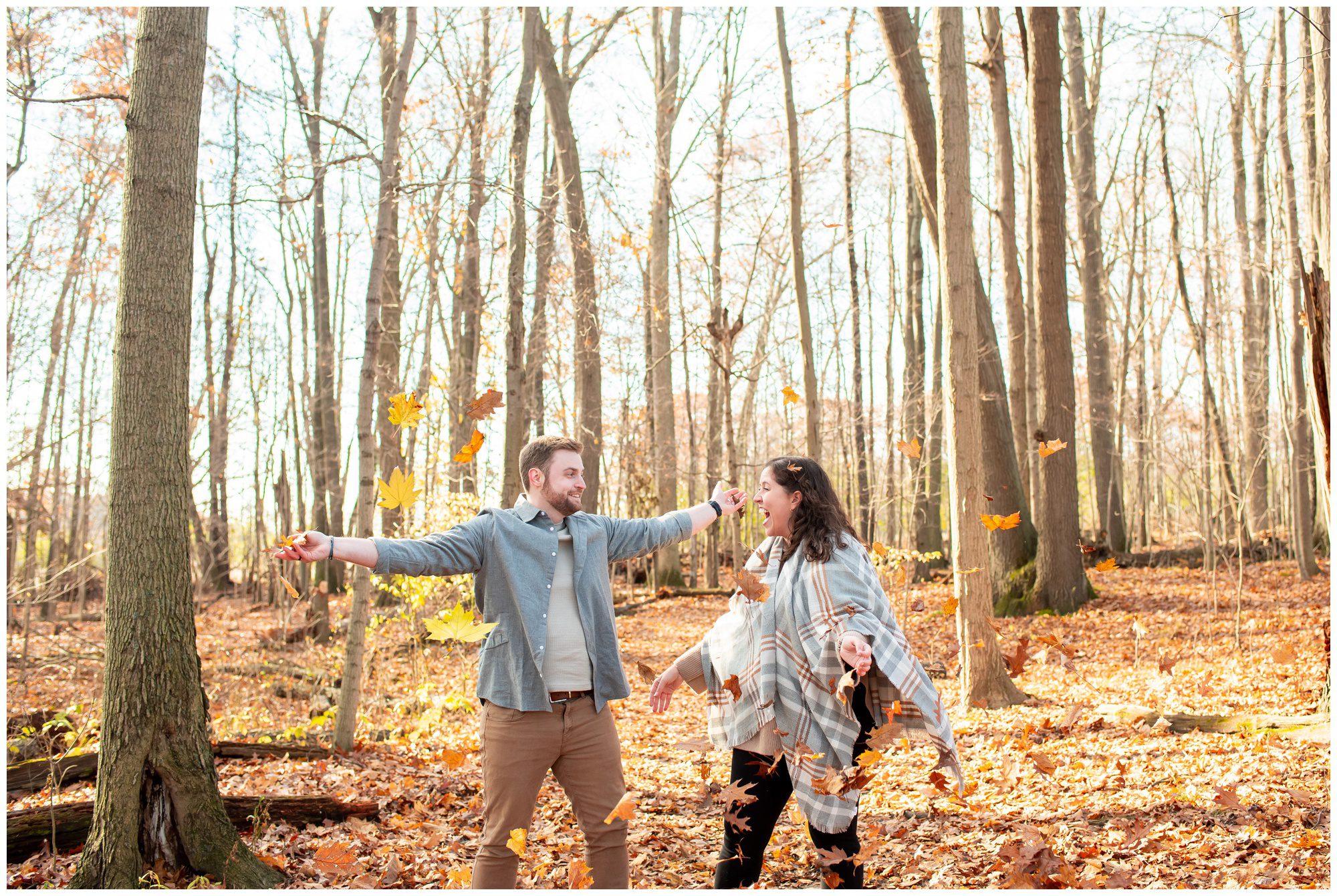 Couple throwing leaves in the woods together at Komoka Provincial Park