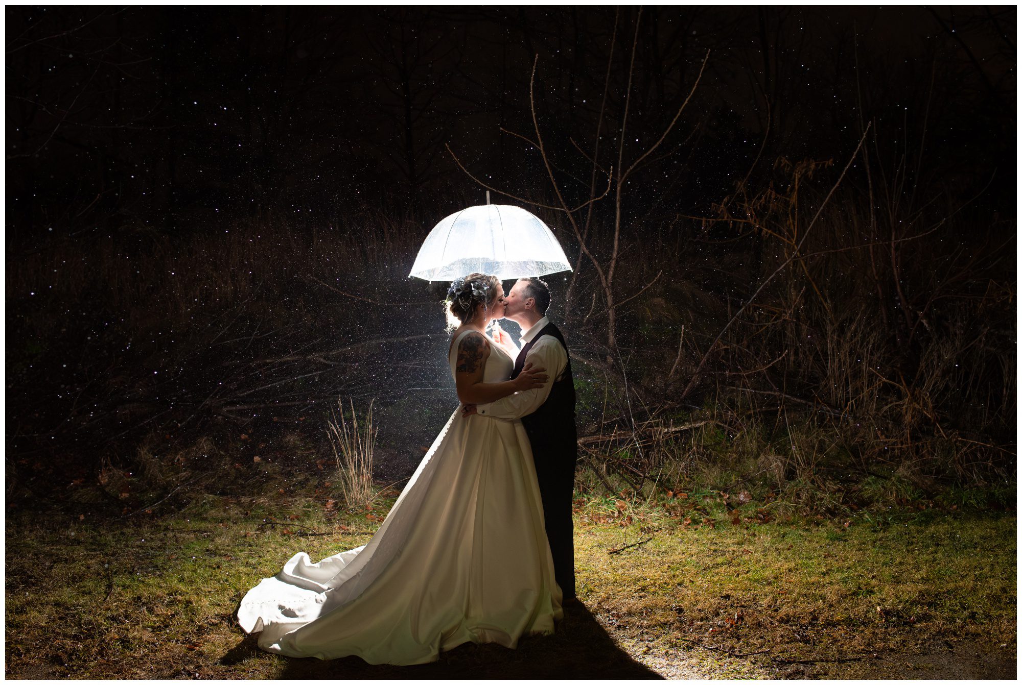 Couple kissing under umbrella at night in the rain in London Ontario.