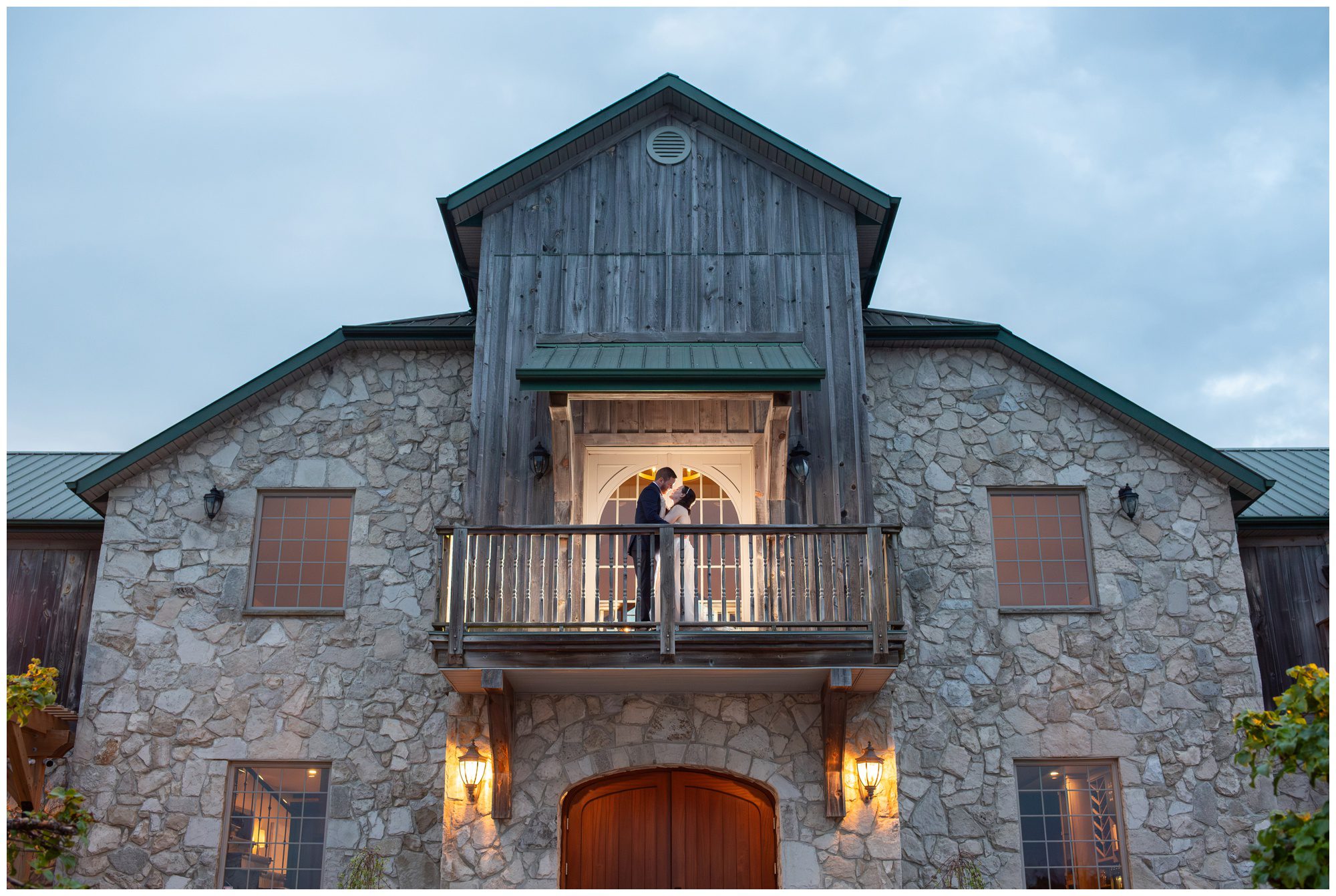 Couple kissing on balcony at dusk at Sprucewood Shores Estate Winery in Amherstburg Ontario