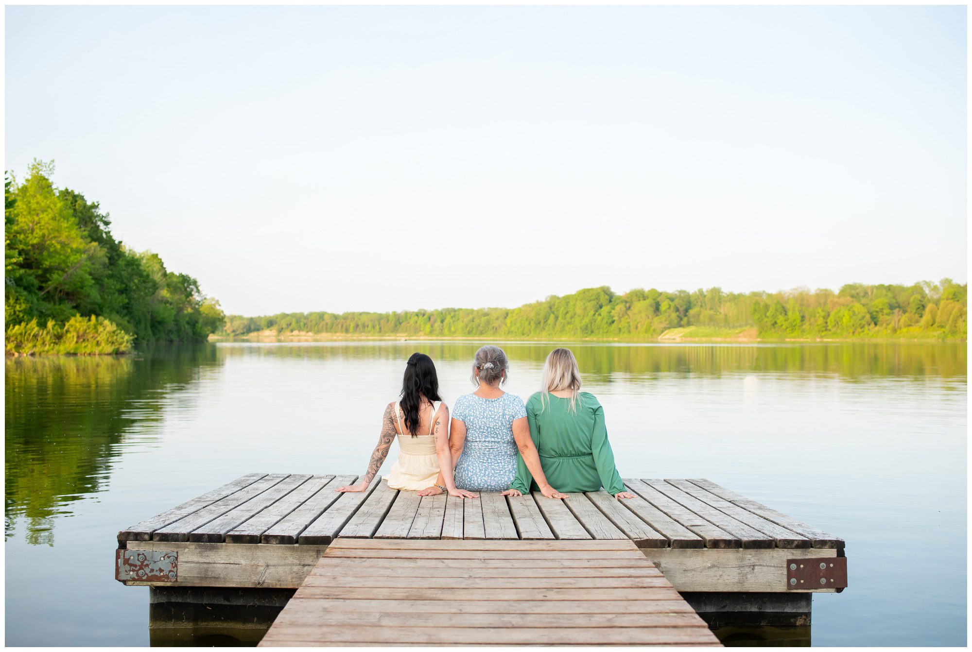 Mom and her two daughters sitting at the end of a dock looking out at the water at Fanshawe Conservation Area.